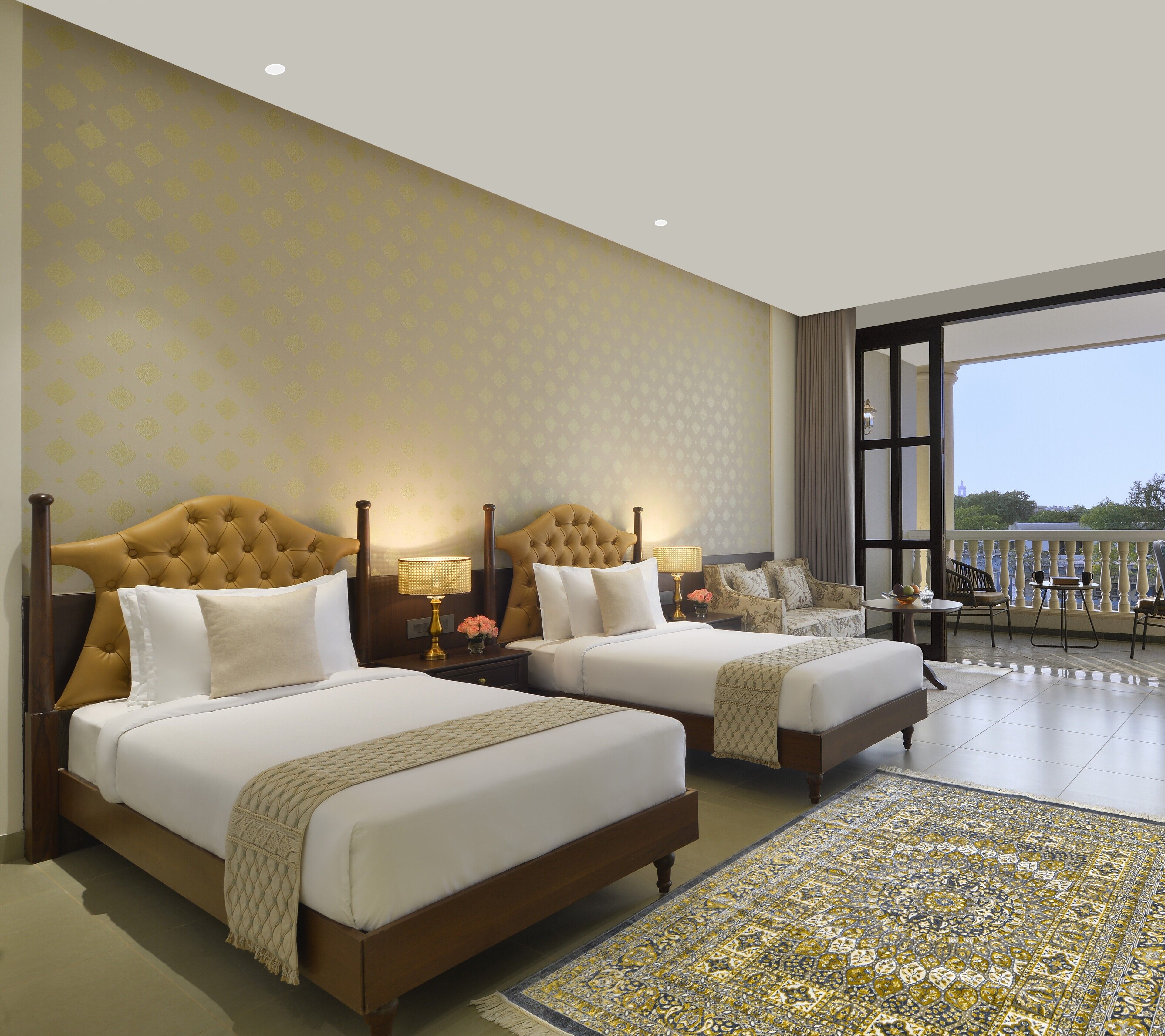 Une chambre d’hôtel avec deux lits, un balcon avec vue et un tapis à motifs.