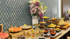 A buffet with various food items and a decorative flower arrangement. - The Fort House, Diu- IHCL SeleQtions (Diu)