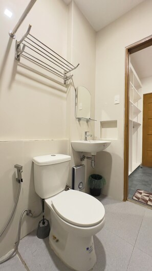 A modern bathroom with a toilet, sink, and towel rack. - The Palawans Place-b&b (Puerto Princesa)