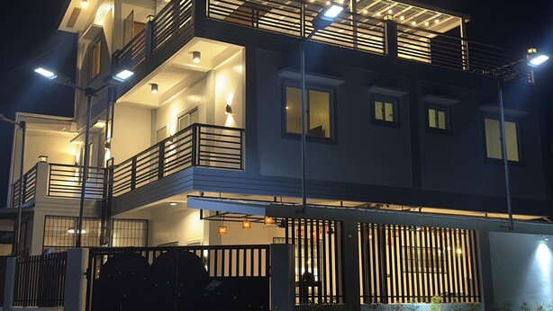 A modern two-story house with a balcony, a gated entrance, and a well-lit exterior. - The Palawans Place-b&b (Puerto Princesa)