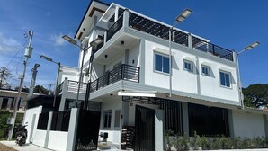 A modern two-story building with a balcony, a gated entrance, and solar street lights. - The Palawans Place-b&b (Puerto Princesa)