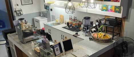 A modern bar area with a granite countertop, hanging lights, and a variety of beverages.