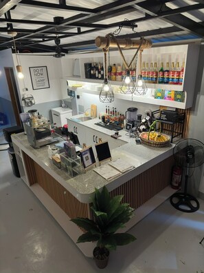 A modern bar area with a granite countertop, hanging lights, and a variety of beverages. - The Palawans Place-b&b (Puerto Princesa)