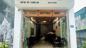 L’entrée de l’hôtel TOTO CHAN, avec un espace de réception, un escalier et une salle à manger visibles à l’intérieur.