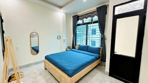 A bedroom with a wooden bed, a mirror, a window with curtains, and a door.