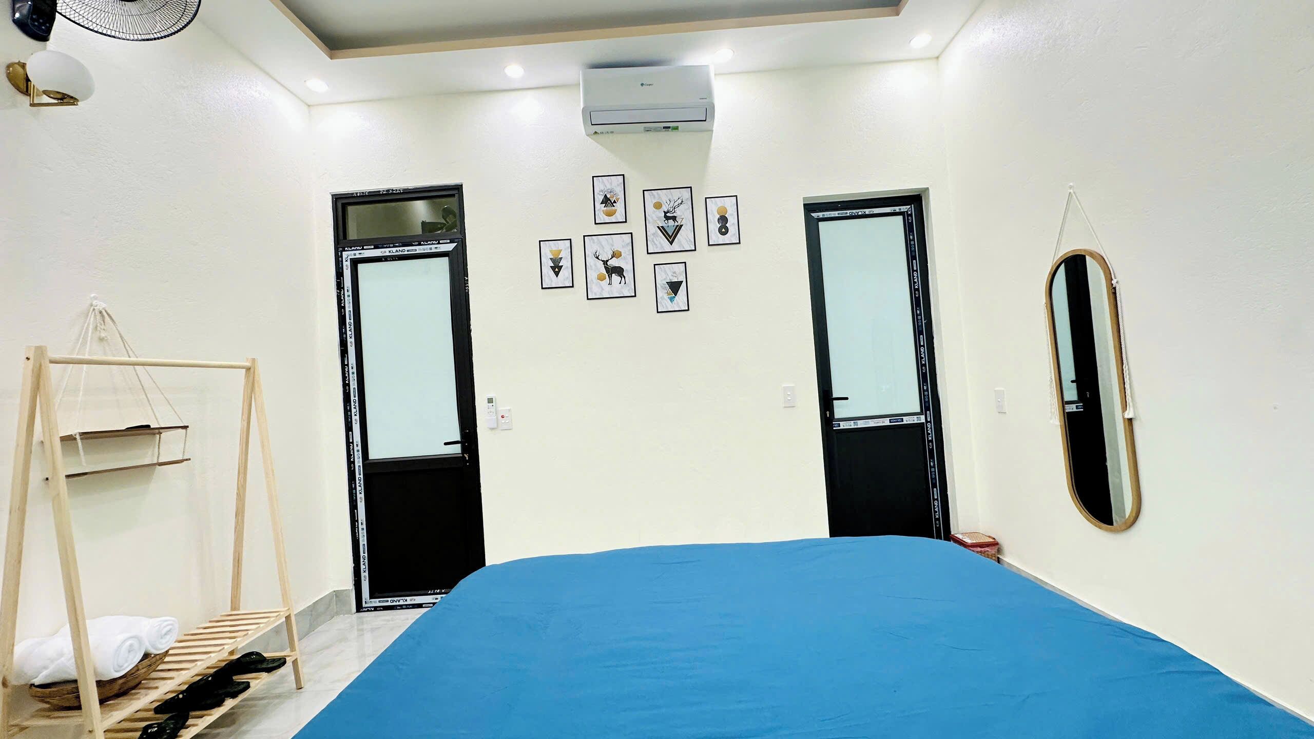 A bedroom with a bed, two doors, a mirror, and a wall-mounted air conditioner.