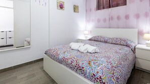 A bedroom with a large bed, a bedside table with a lamp, a window with curtains, and a wall with artwork. - 309 Acapulco Playa de Las Americas (Playa de las Américas)