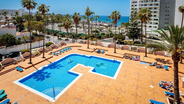 A resort pool with sun loungers and palm trees, overlooking a beach and cityscape. - 309 Acapulco Playa de Las Americas (Playa de las Américas)