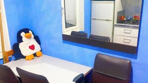 A room with a blue wall, a white table, two black chairs, and a penguin plush toy. - Giovanni Giolitti 177 Termini (Rome)