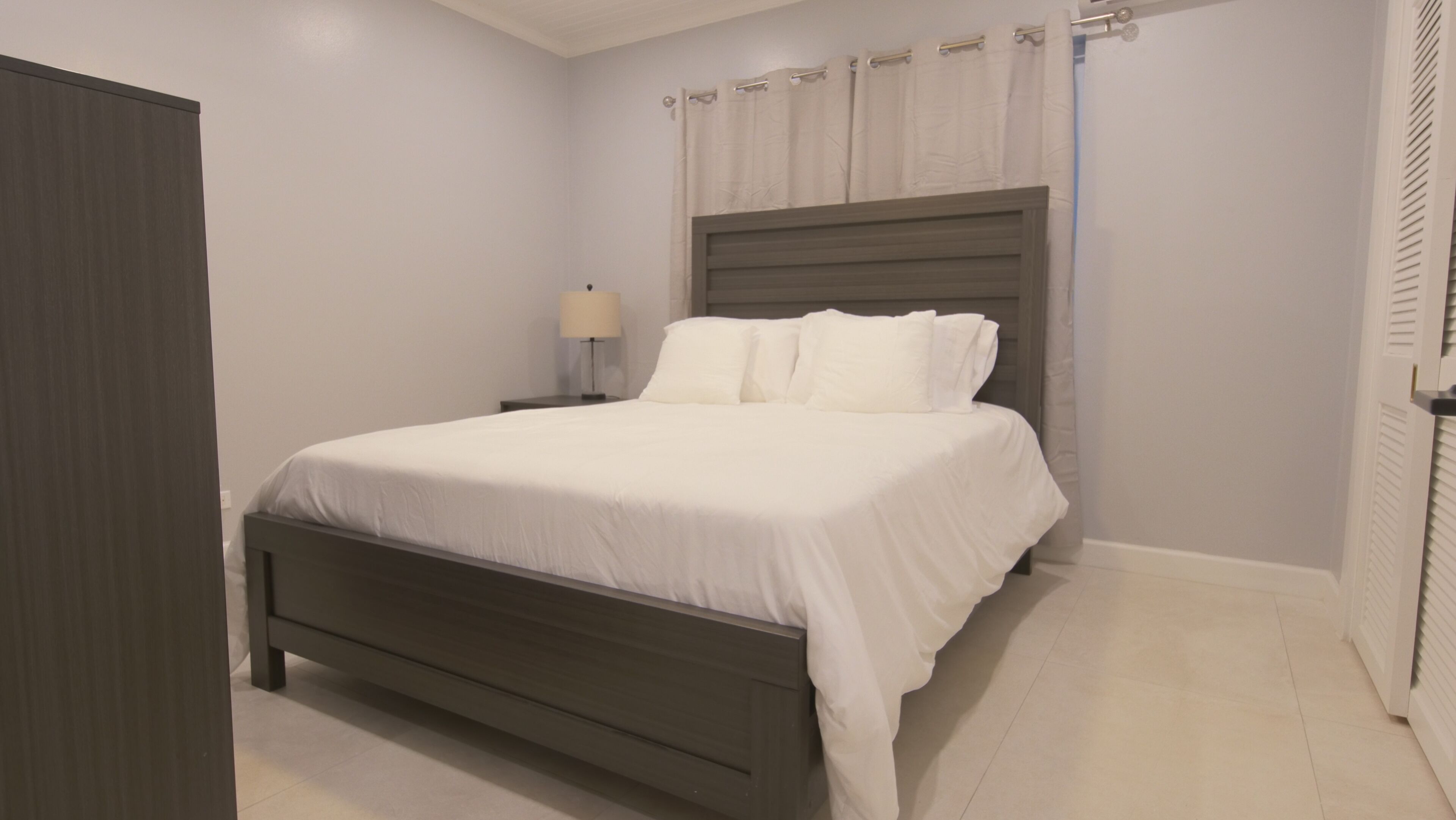 A bedroom with a bed, nightstand, lamp, and a wardrobe.