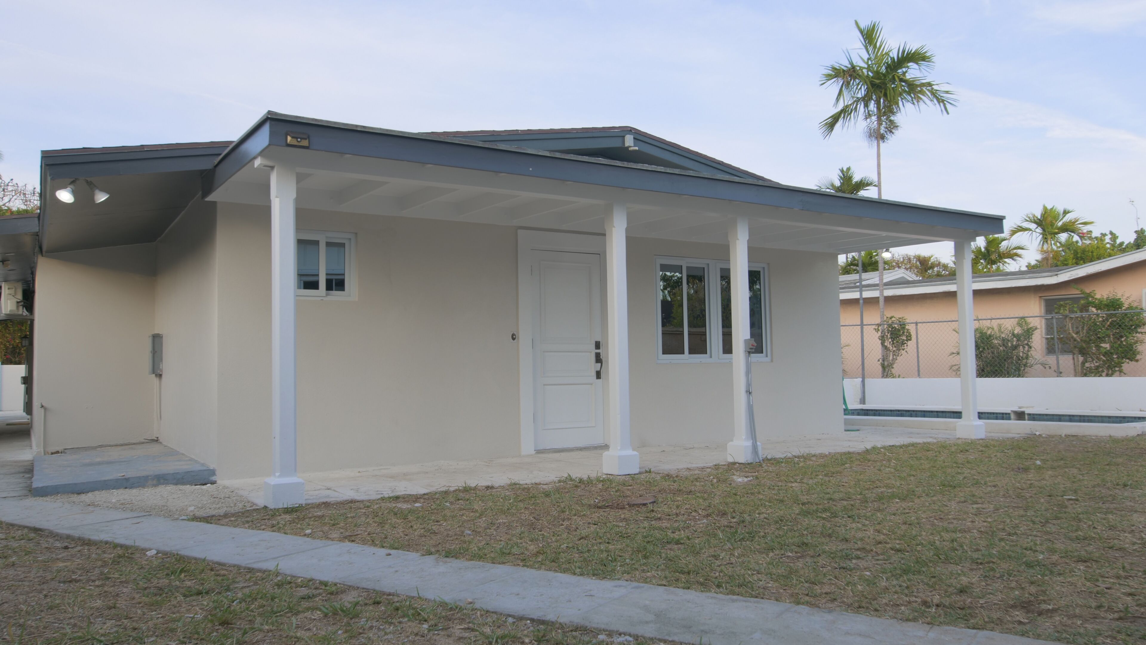 A single-story house with a covered porch, a front door, and a small window.