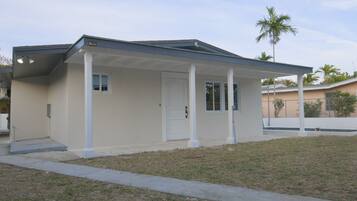 A single-story house with a covered porch, a front door, and a small window.