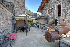 Un bâtiment en pierre doté d’une terrasse, d’un barbecue et offrant une vue sur les montagnes.