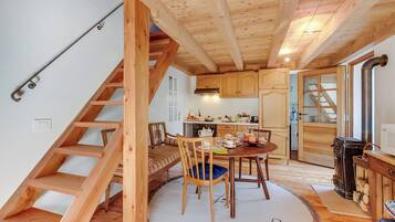 Ein Holzinnenraum mit Treppe, einem Essbereich mit rundem Tisch und Stühlen sowie einer Küche mit Holzschränken und Herd.