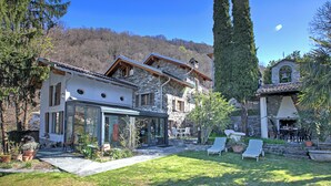 A stone house with a glass-enclosed patio, outdoor seating, and a bell tower.