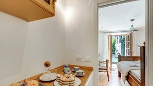 Et køkken med frugtskål, kaffemaskine og spisebord.