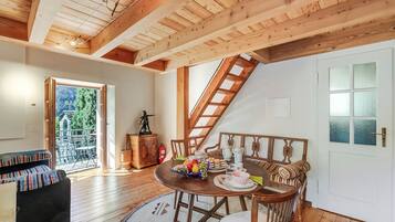 Ein gemütlicher Raum mit Holzboden, einem Tisch gedeckt mit Speisen, einer Couch und einer Treppe, die in einen oberen Bereich führt.
