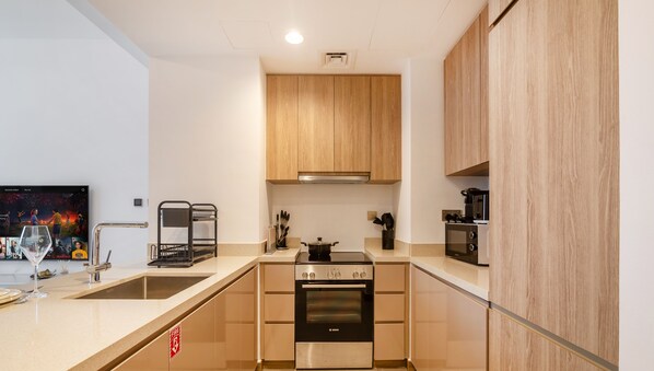 Eine moderne Küche mit Holzausstattung, einem Bosch-Ofen, einer Mikrowelle und einem Spülbecken.