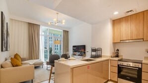 A modern kitchen with a Bosch oven, a dining area with a sofa and a TV displaying 'Stranger Things'. - 1BR Apt Urban Oasis near Dubai Mall (Dubai)