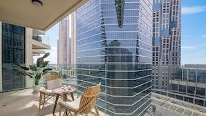 A balcony with a glass railing, wicker chairs, a small table, and a potted plant. - 1BR Apt Urban Oasis near Dubai Mall (Dubai)