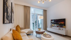 A modern living room with a sofa, a coffee table, and a TV displaying 'Stranger Things'. - 1BR Apt Urban Oasis near Dubai Mall (Dubai)
