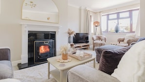 Een gezellige woonkamer met een open haard, een televisie en comfortabele zitplaatsen.