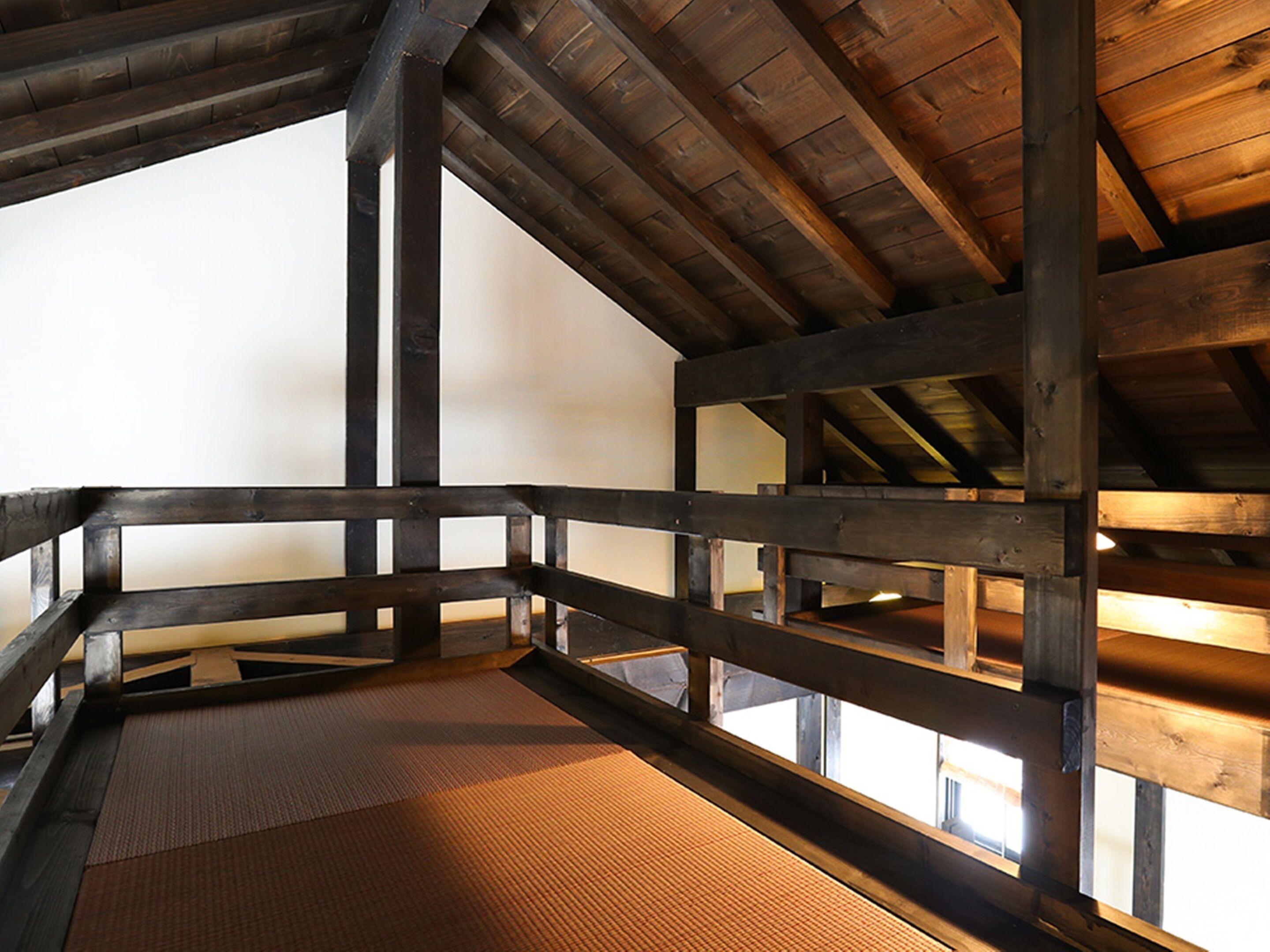 A wooden interior with a high ceiling and a view of the sky through a window.