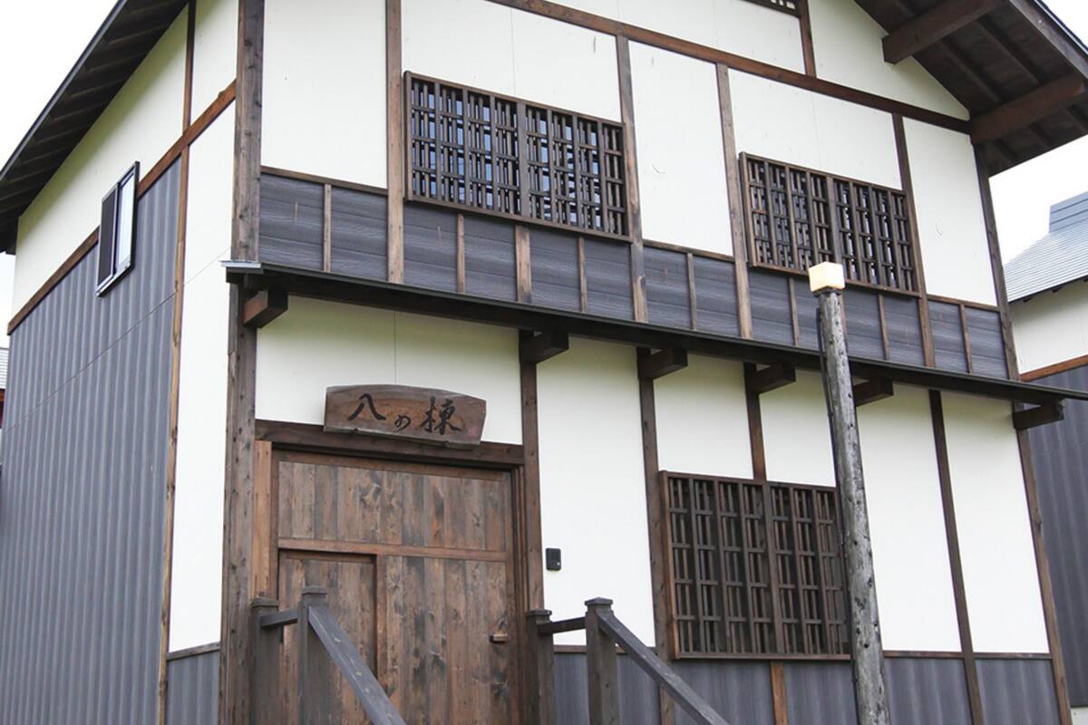 A traditional Japanese building with a wooden door, a sign above the door, and a balcony with a wooden railing.