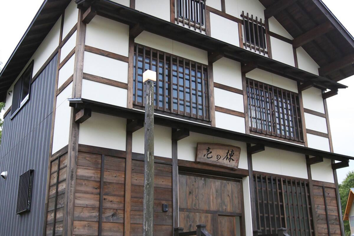 A traditional Japanese building with a wooden facade, multiple windows with bars, and a sign with Japanese characters.