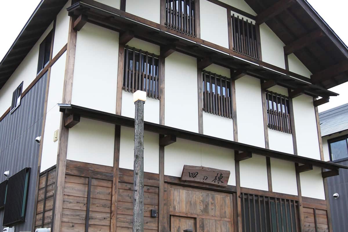 A traditional Japanese building with a wooden facade, multiple windows with bars, and a sign with Japanese characters.