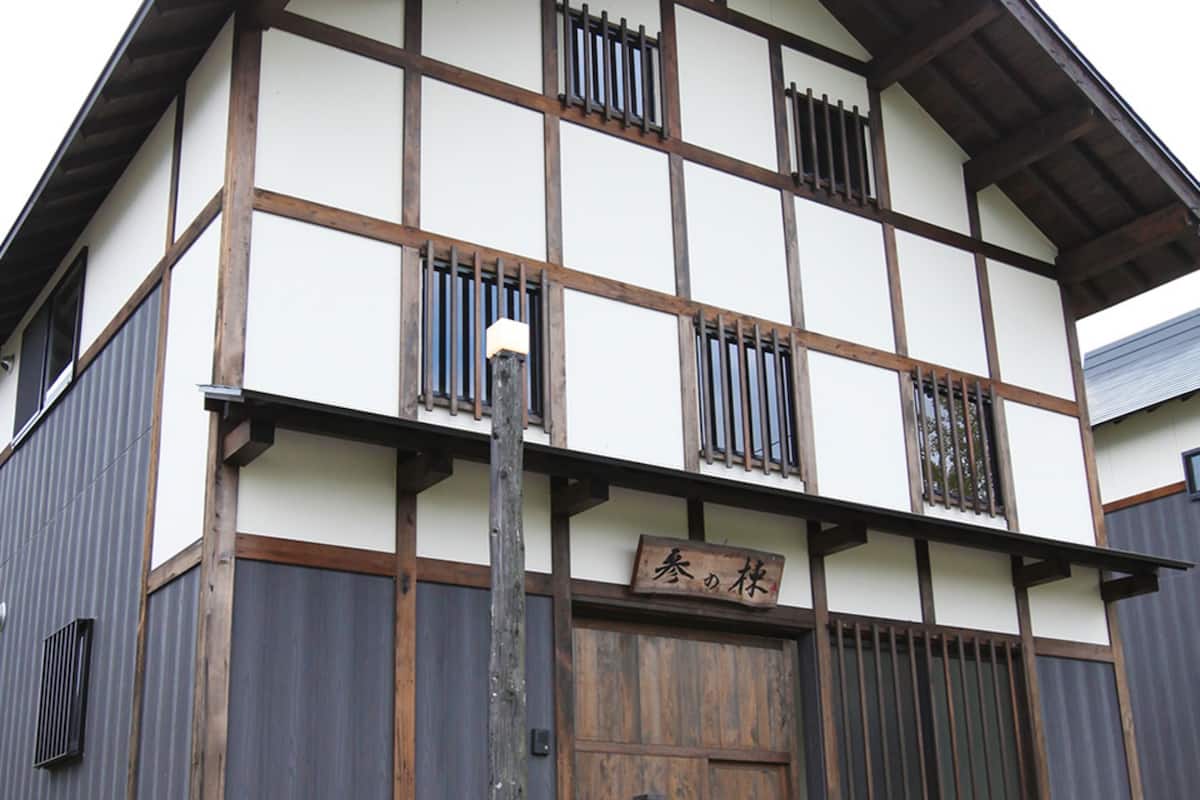 A traditional Japanese building with a wooden facade, multiple windows, and a sign above the entrance.