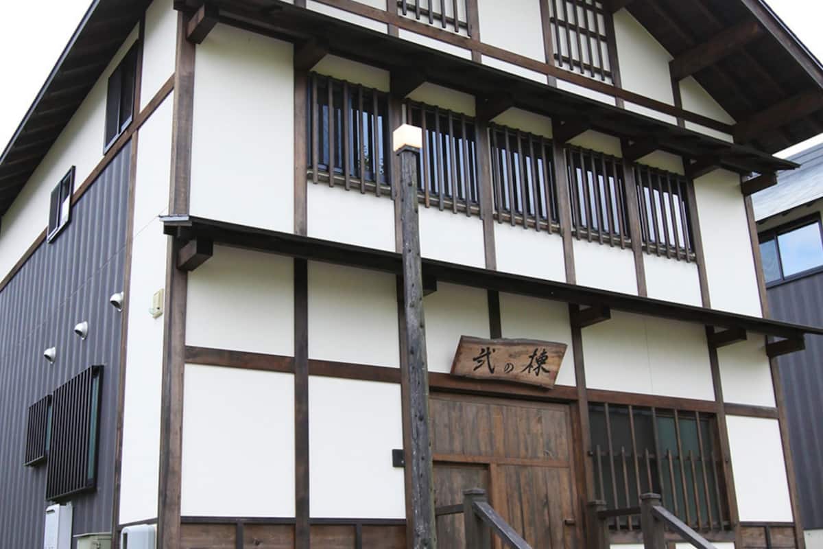 A traditional Japanese building with a wooden exterior, a sign with Japanese characters, and a staircase leading to the entrance.