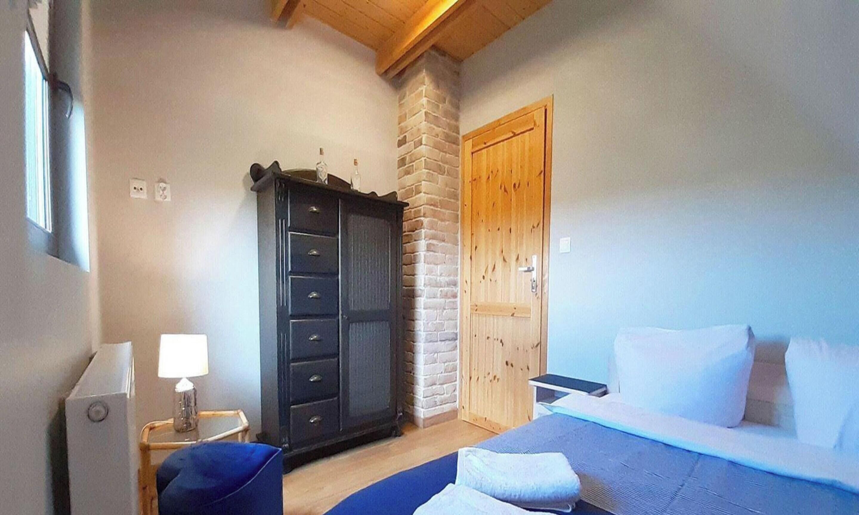 A bedroom with a bed, a dresser, a lamp, and a wooden door.