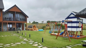 Een woonhuis met een huis van twee verdiepingen, een speelruimte met een schommel en een klein speeltuintje.