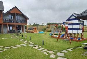 Una propiedad residencial con una casa de dos pisos, un área de juegos con un columpio y una casita.