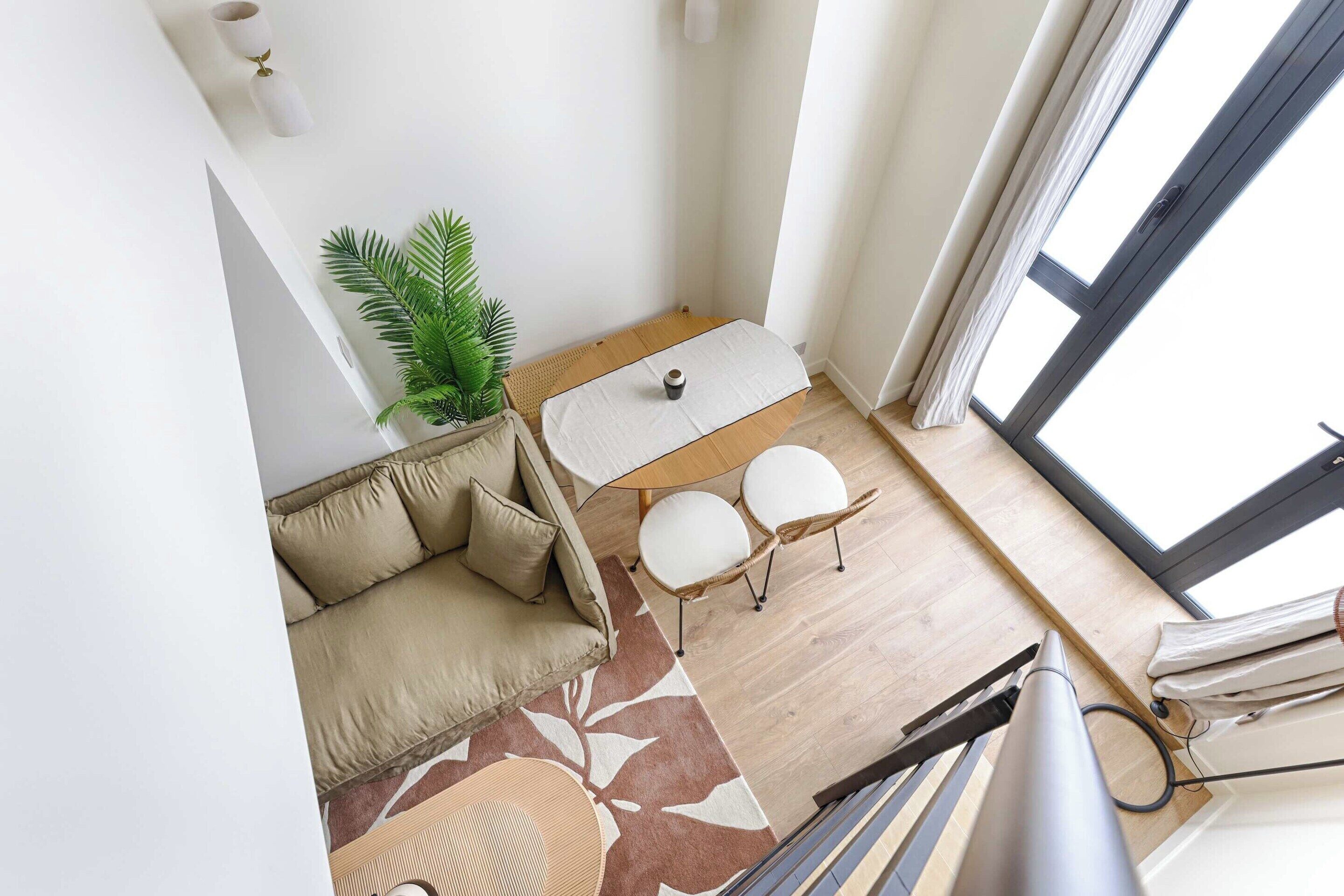 Una sala de estar moderna con un sofá, dos sillones, una mesita, una planta y un ventanal grande.