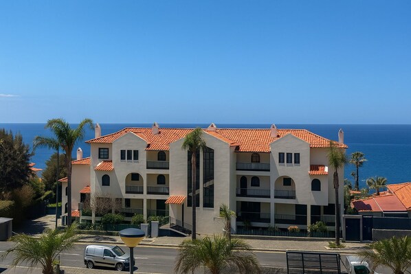 Ein mehrstöckiges Hotel mit rotem Ziegeldach, Balkonen und Blick auf den Ozean.