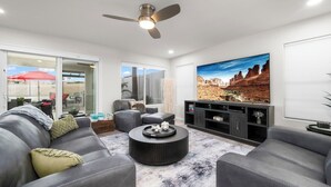 A modern living room with a grey sofa, a round coffee table, and a flat-screen TV. - Par-Fect Views | Red Mountain Golf Course, Heated Pool , Incredible Red Mountain Views (Mesa)
