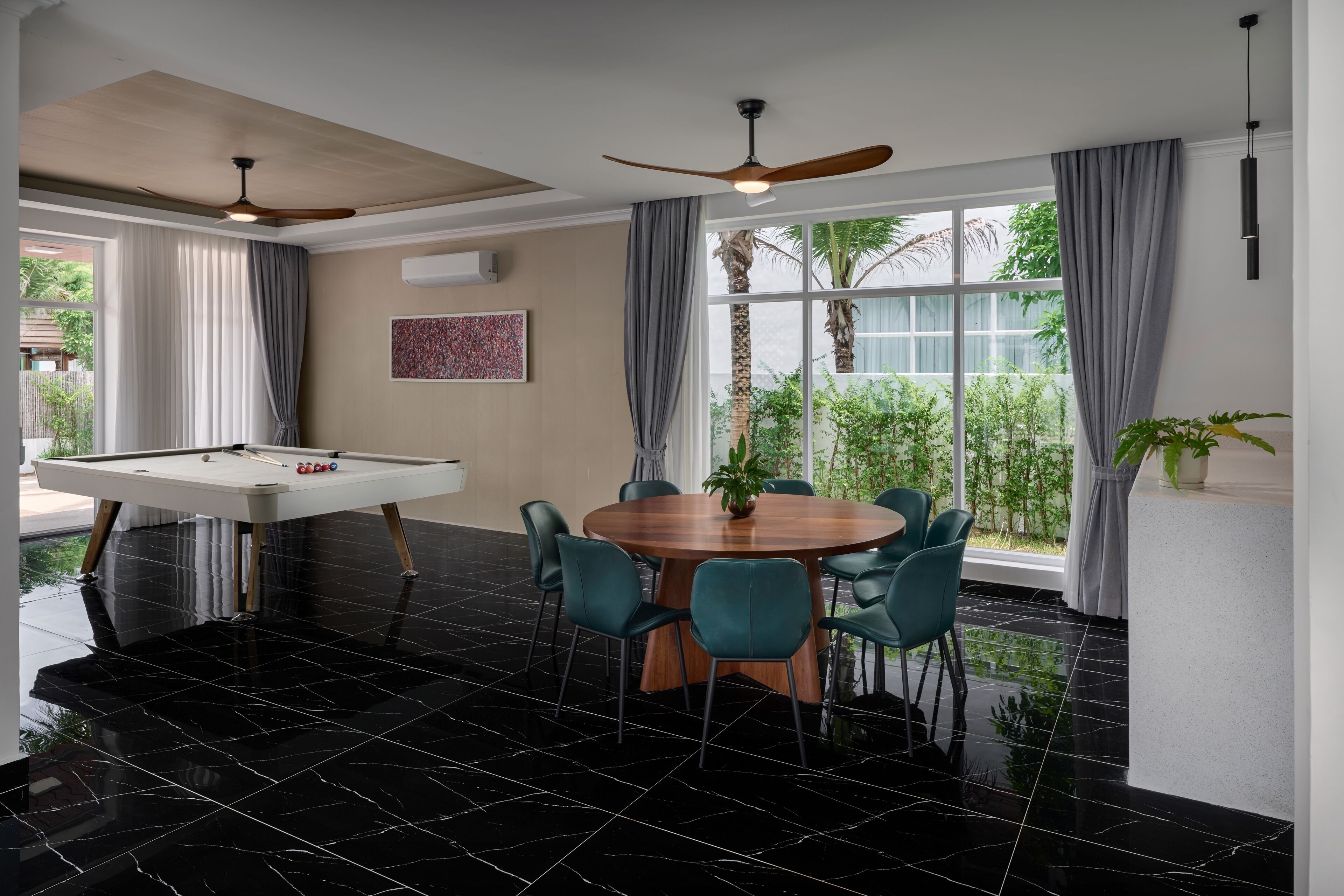 Una habitación con mesa de billar, una mesa de comedor redonda con sillas y un ventilador de techo.