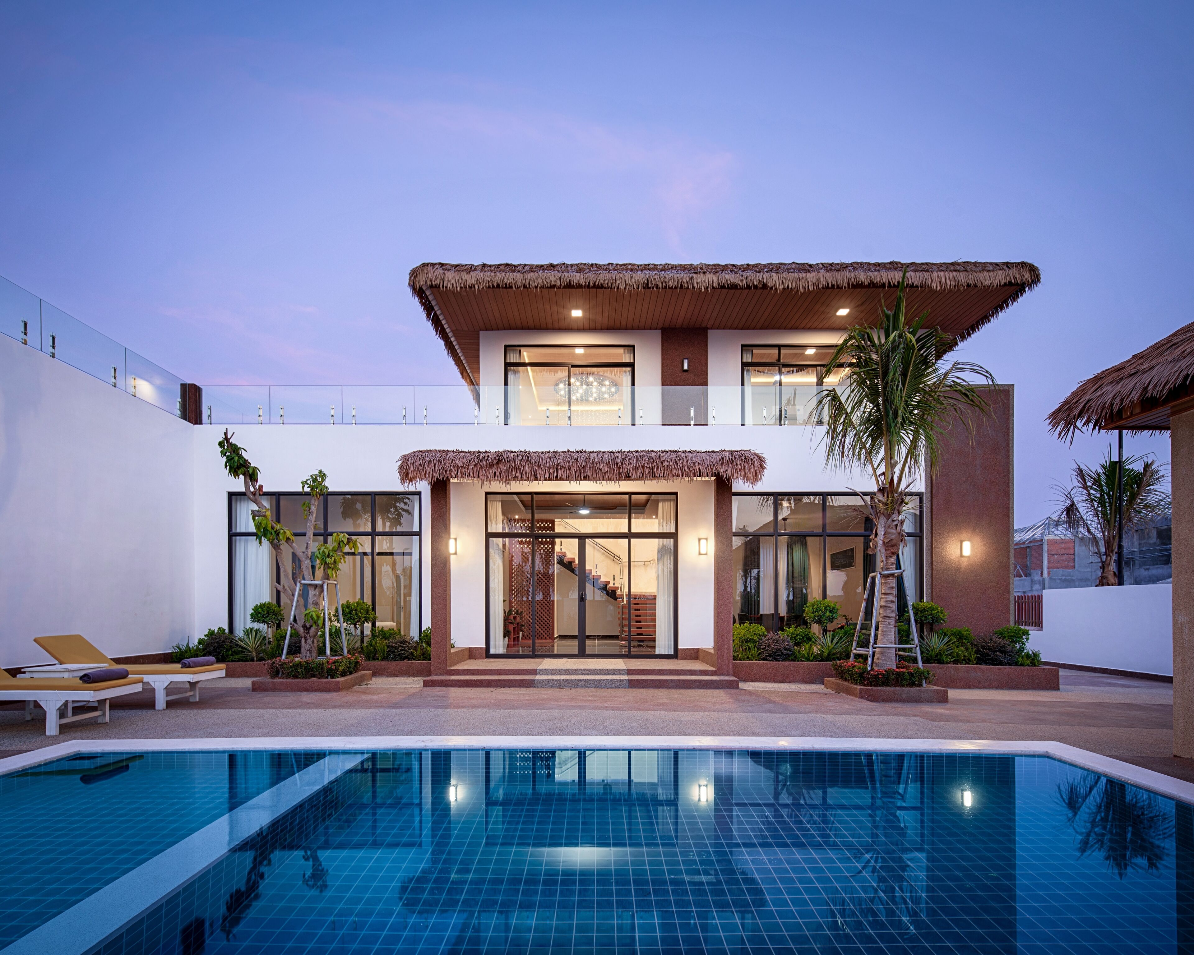 Una casa moderna de dos pisos con piscina, ventanas amplias y una escalera que conduce al nivel superior.