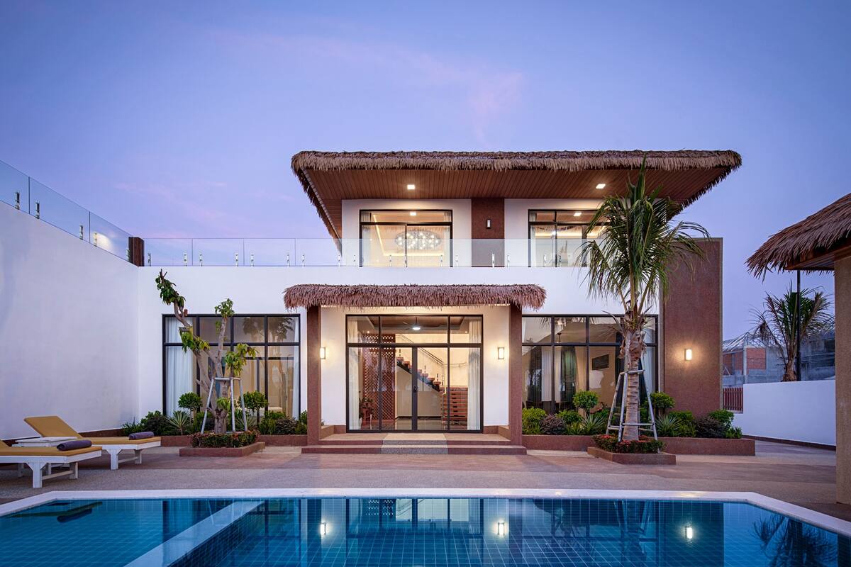 Uma casa moderna de dois andares com piscina, janelas amplas e escadaria para o andar superior.