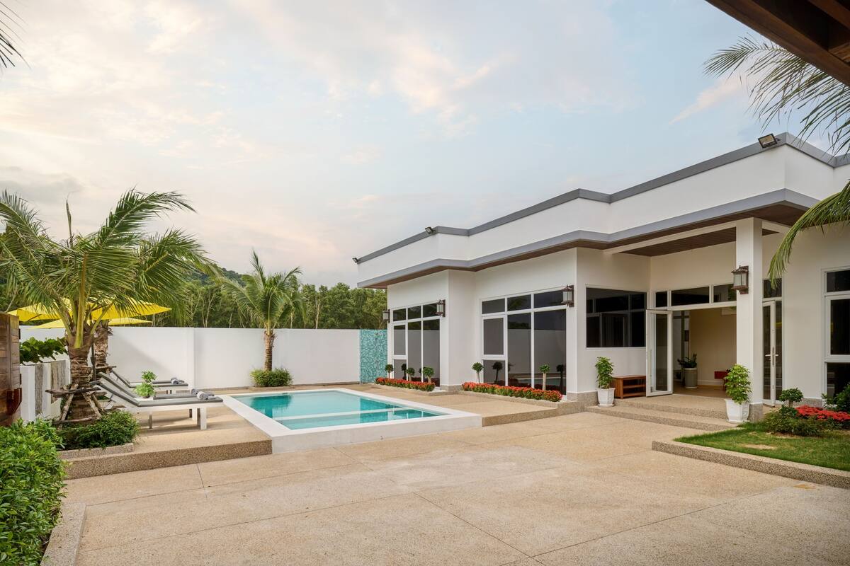 Una casa moderna con piscina, un porche cubierto y un jardín bien cuidado.