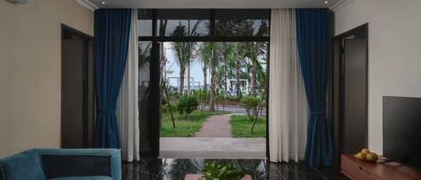Una sala de estar moderna con un sofá, una mesa de centro con una planta y un televisor sobre un mueble de madera.