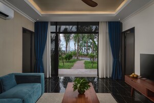 Una sala de estar moderna con un sofá, una mesa de centro con una planta y un televisor sobre un mueble de madera.