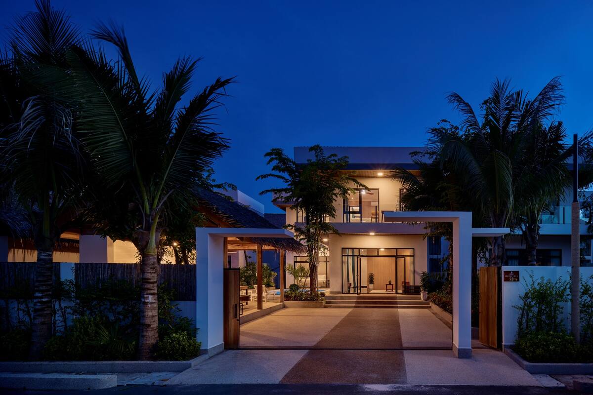 Una casa moderna de dos pisos con una entrada bien iluminada y un espacio al aire libre cubierto.