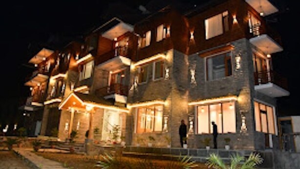 A multi-story hotel with a stone facade, multiple balconies, and warm exterior lighting. - Mountain Majesty Manali (Manali)