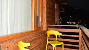 A wooden cabin with a balcony, a window, and a chair. - Mountain Majesty Manali (Manali)