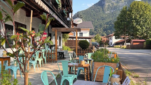 An outdoor seating area with tables and chairs, surrounded by greenery and flowers. - Your home in the Bavarian Alps - Spacious vacation on 90 m² with wellness (Flintsbach am Inn)