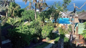 A tropical resort with a swimming pool, palm trees, and a view of the ocean.