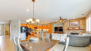 A spacious living area with a dining table, chairs, a sofa, and a kitchen in the background. - Gazebo + Putting Green: Serene Indio Getaway (Indio)